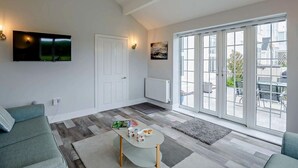 Un salon moderne avec un téléviseur, un canapé et une grande fenêtre donnant sur un beau paysage.