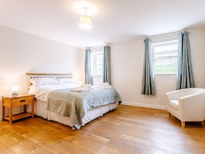 A bedroom with a bed, bedside table, lamp, chair, and windows with curtains. - 6 Bed in Dorchester (oc-lampd) (Sydling Saint Nicholas)