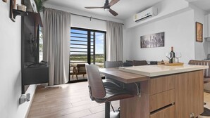 Eine moderne Küche mit einer zentralen Kochinsel, Barhocker, einem Deckenventilator und einem großen Fenster mit Blick hinaus.