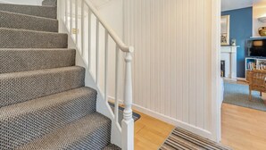 Una escalera con alfombra estampada, barandillas blancas y piso de madera.