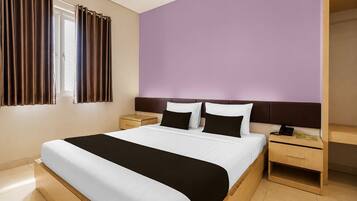 Habitació d'hotel amb un llit gran, dues taules de nit, un armari i una finestra amb cortines.
