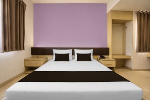 A hotel room with a large bed, two bedside tables, a wardrobe, and a bathroom. - Townhouse Oak Hotel Niaga Surabaya (Surabaya)
