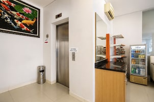 Um saguão de hotel com elevador, lixeira, máquina de vendas automática e refrigerador.