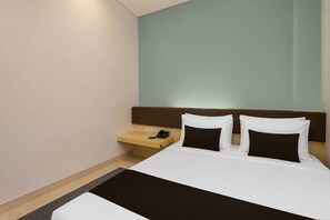 A hotel room with a bed, a nightstand with a phone, and a wall-mounted light. - Townhouse Oak Hotel Niaga Surabaya (Surabaya)