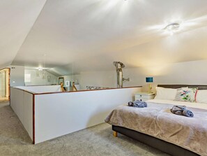 Un dormitorio con un espejo grande, una cama, una mesita de noche e iluminación en el techo.