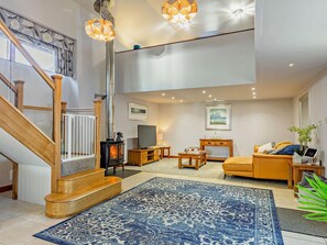 A modern living room with a fireplace, a sofa, a TV, and a staircase. - 1 Bed in Barnstaple (oc-norwo) (Hiscott)