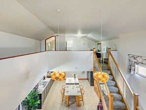 A modern kitchen with a dining area, wooden staircase, and a view of the living room. - 1 Bed in Barnstaple (oc-norwo) (Hiscott)