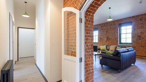 A spacious living area with a brick wall, a sofa, and a door leading to another room. - 3 Bed in Freshwater (oc-78098) (Freshwater)