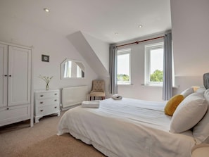 A bedroom with a bed, a chest of drawers, a radiator, a chair, and a window. - 5 Bed in Bude (oc-79150) (Hersham)