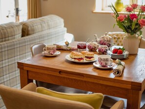 A dining table with tea cups, scones, jam, and strawberries. - 2 Bed in Brecon (oc-42931) (Llanfrynach)