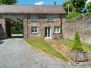 A stone house with a covered porch, a gravel driveway, and a small garden. - 2 Bed in Brecon (oc-42931) (Llanfrynach)