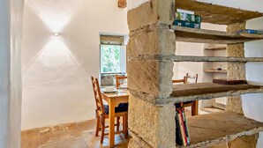 Un coin repas avec une étagère en pierre, des chaises en bois et une table.