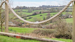 Una tanca de corda amb vista a un paisatge rural, incloent camps i edificis a la distància.