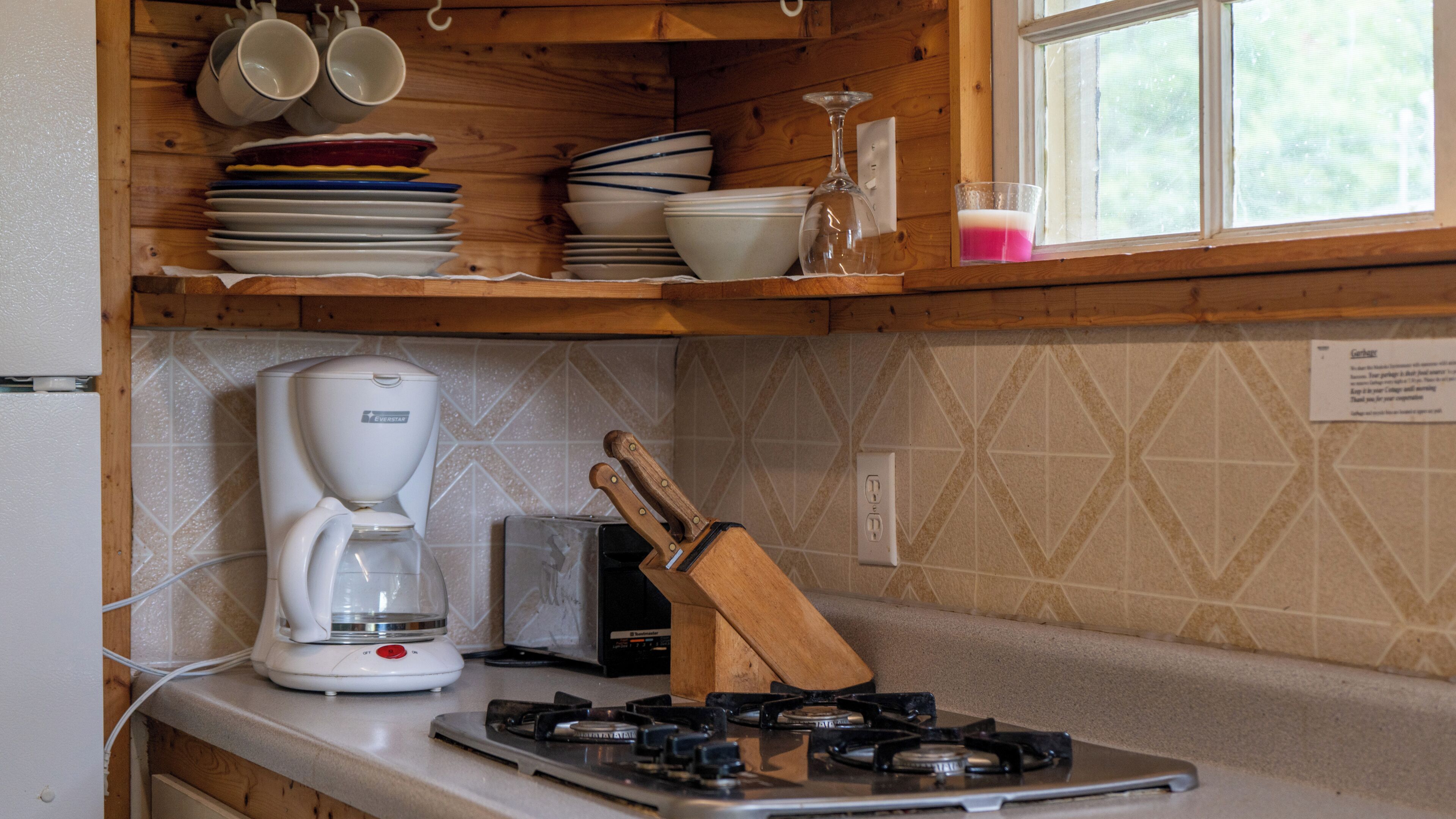 A kitchen with a coffee maker, a knife block, and a gas stove.