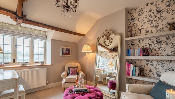 A room with a large mirror, a plush ottoman, a white sofa, a bookshelf, and a radiator. - 1 Bed in Brecon (oc-42942) (Llanfrynach)