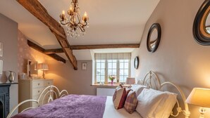 A bedroom with a bed, a chandelier, a dresser, a window, and a radiator. - 1 Bed in Brecon (oc-42942) (Llanfrynach)