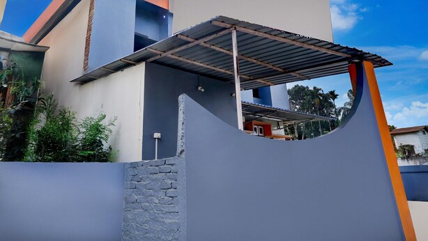 Un edificio moderno con un diseño arquitectónico único, que incluye un espacio exterior cubierto y una pared de piedra.