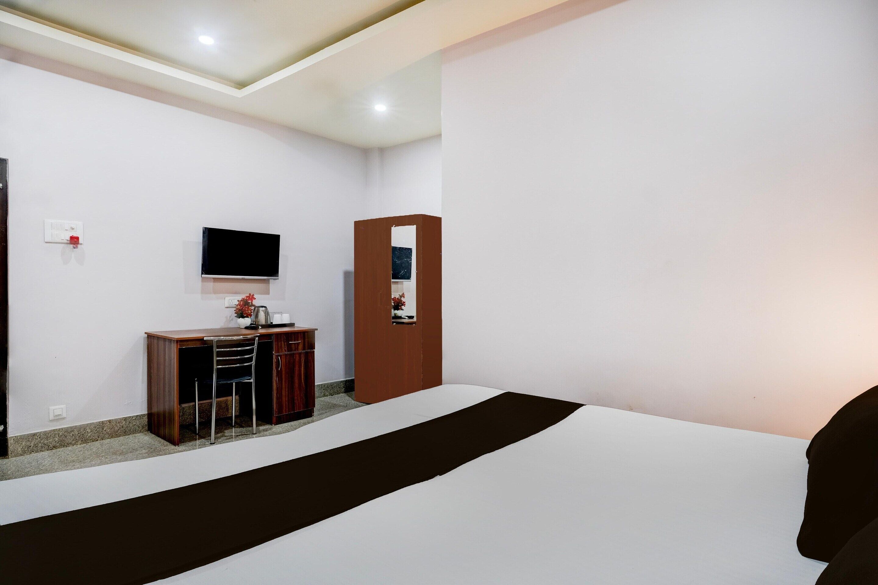 Une chambre d’hôtel comprenant un lit, un bureau avec une chaise, une télévision et un miroir.