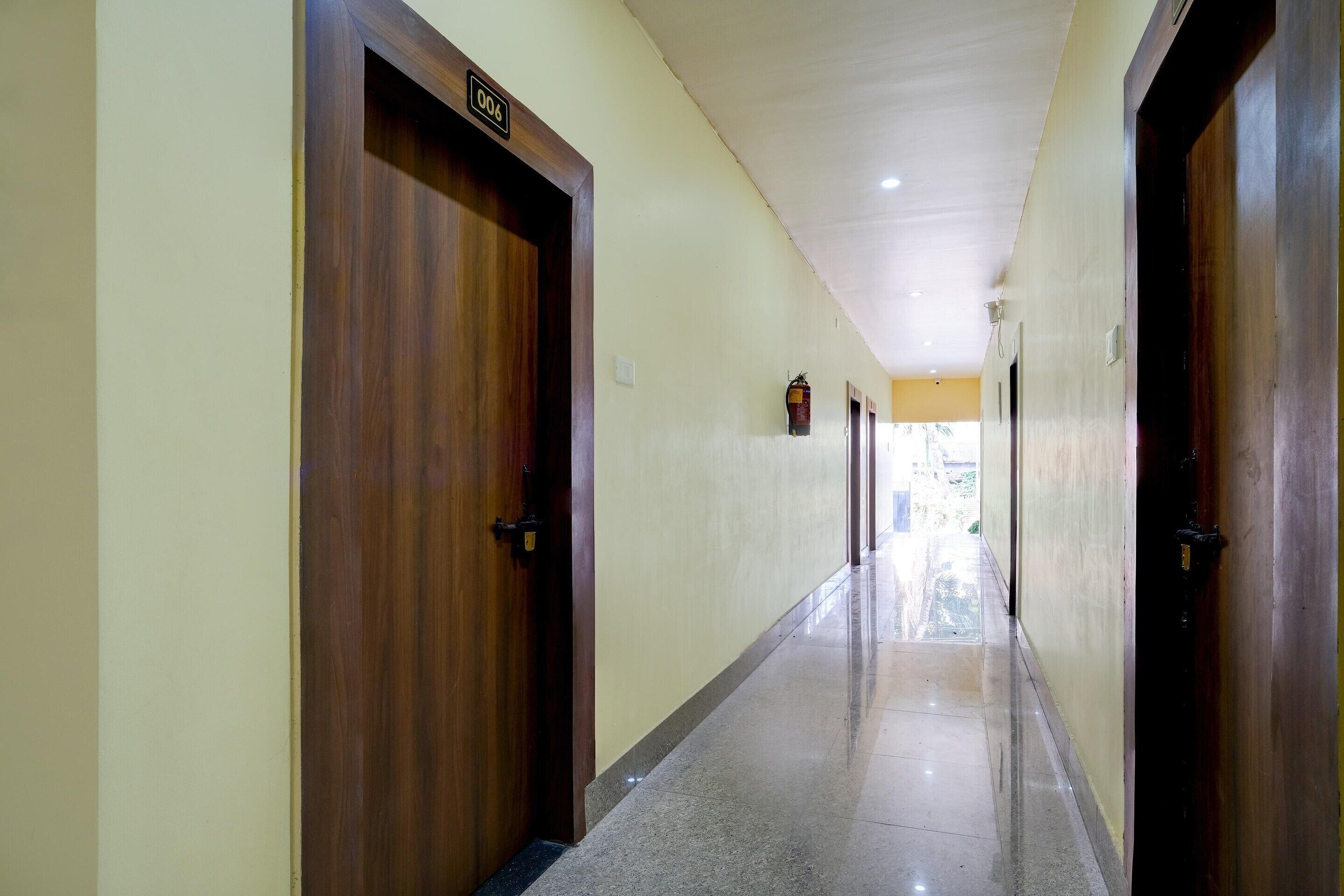 Un pasillo con puertas de madera, un letrero con número y suelo de baldosas.