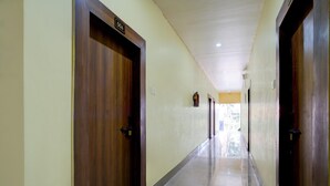 Un pasillo con puertas de madera, un letrero con número y suelo de baldosas.