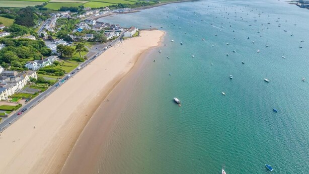 An aerial view of a coastal area with a sandy beach, a residential area with houses, and a marina with numerous boats. - 2 Bed in Barnstaple (oc-linor) (Hiscott)