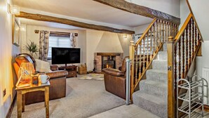 A living room with a fireplace, a television, and a staircase. - 2 Bed in Barnstaple (oc-linor) (Hiscott)