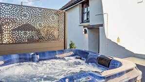 A hot tub with a wooden deck, a white wall, and a decorative screen. - 2 Bed in Barnstaple (oc-linor) (Hiscott)