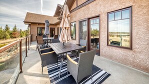 En patio med et bord og stole, en overdækket parasol og udsigt over det omkringliggende landskab.