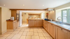 Una cocina moderna con armarios de madera, una isla central, horno empotrado y ventana con vista al jardín.