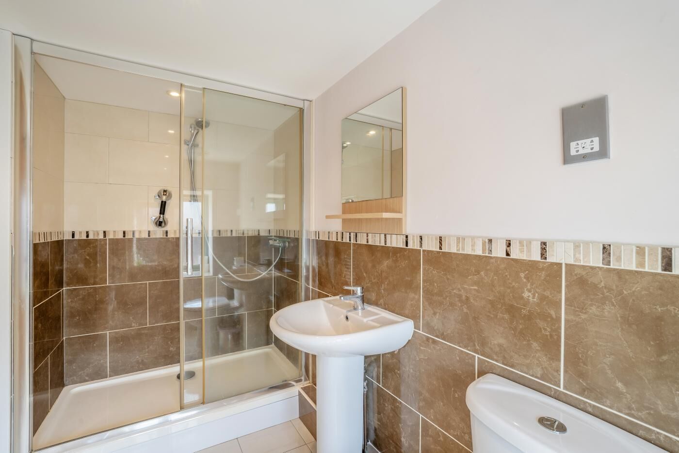A bathroom with a glass-enclosed shower, a pedestal sink, and a toilet.