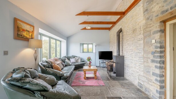 Una sala de estar acogedora con una pared de piedra, una chimenea y un sofá de cuero.