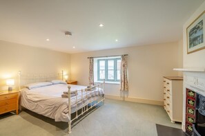 A bedroom with a bed, bedside tables, a dresser, a window with curtains, and a fireplace. - 5 Bed in Wells (oc-64472) (Yarley)