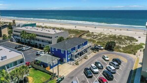 Un hotel junto a la costa con aparcamiento, vistas a la playa y un edificio de fachada azul.