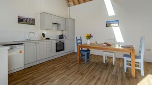 Una cocina moderna con armarios blancos, una mesa de comedor de madera y sillas azules.