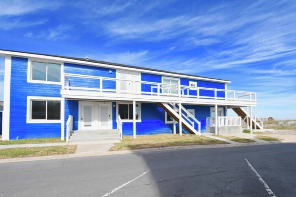 A two-story building with a blue exterior, a front porch, and a staircase leading to the upper level.