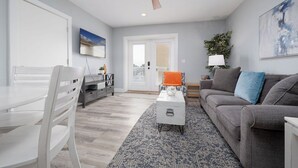 Un salón moderno con un sofá gris, una mesa de centro blanca y una alfombra estampada.