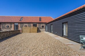 A building with a gravel driveway, a wooden gate, and a red-tiled roof. - 2 Bed in Barrow (oc-b42642) (Barrow)