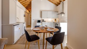 Eine moderne Küche mit weißen Schränken, einem Holztisch und schwarzen Stühlen.