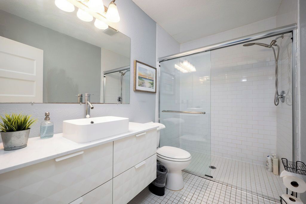 Ein modernes Badezimmer mit Waschbecken, Spiegel und Duschkabine aus Glas.