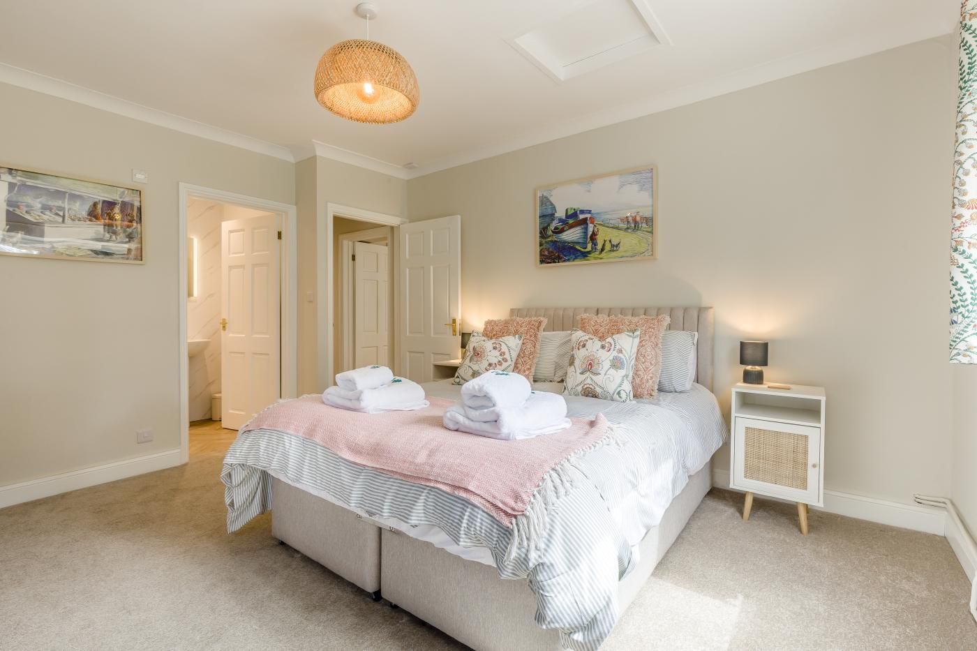 A bedroom with a bed, bedside tables, a hanging light fixture, and a painting on the wall.