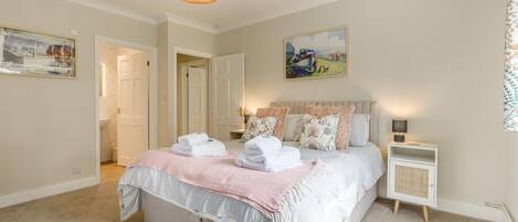 A bedroom with a bed, bedside tables, a hanging light fixture, and a painting on the wall.