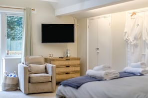 Un dormitori amb un llit, una cadira, una televisió, un armari i una finestra amb cortines.