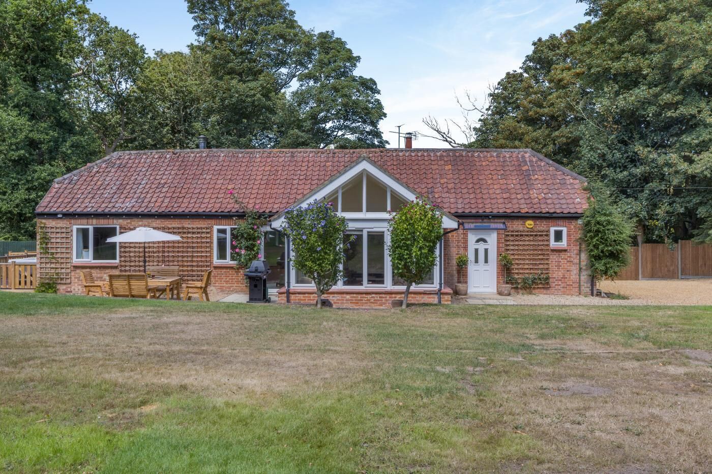 A brick house with a tiled roof, a front porch, and a small garden.