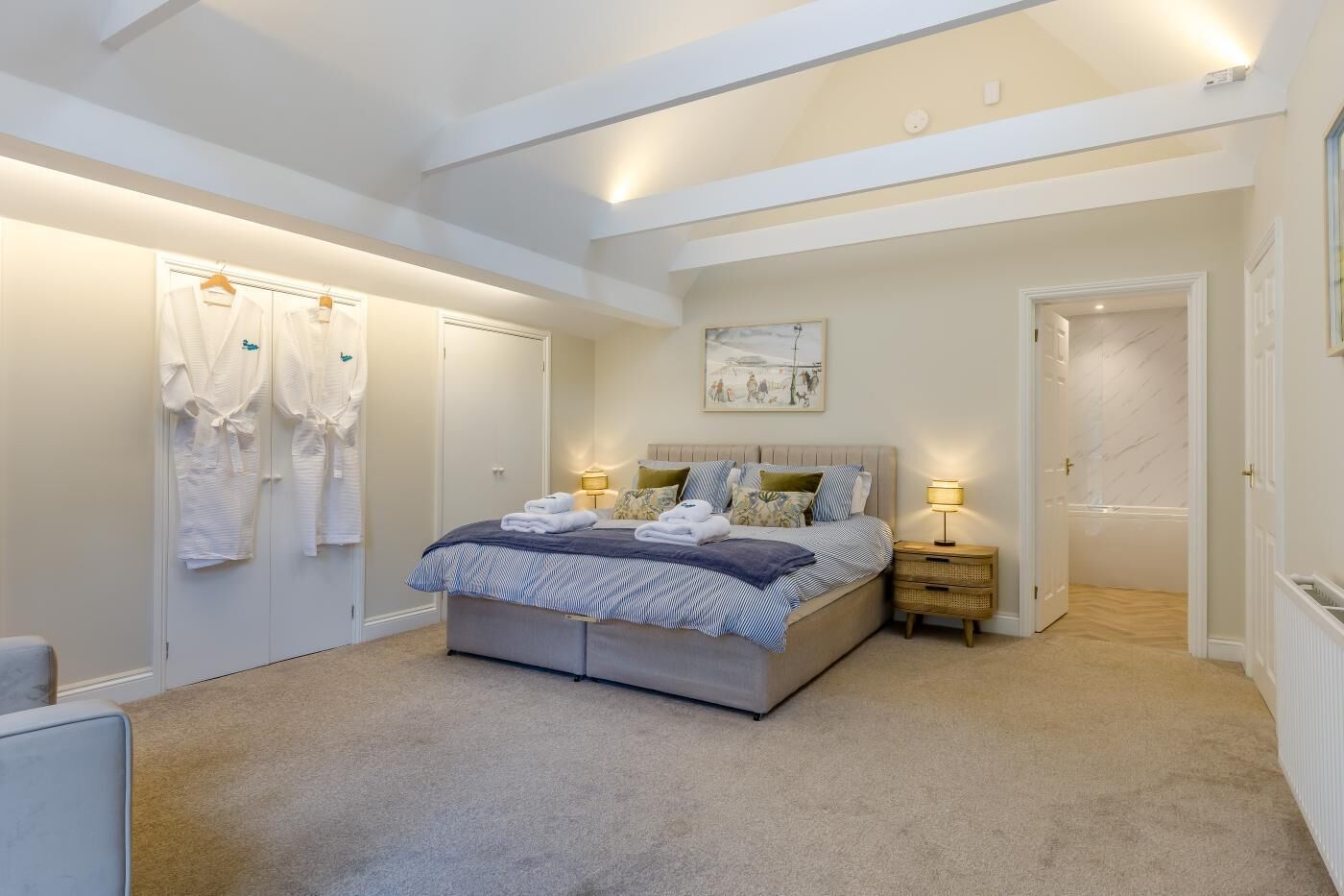 Ein Schlafzimmer mit einem Bett, Nachttischlampen, einem Kleiderschrank und einem Bild an der Wand.