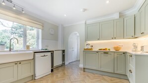 Une cuisine avec des meubles de couleur claire, un lave-vaisselle et une fenêtre avec des stores.