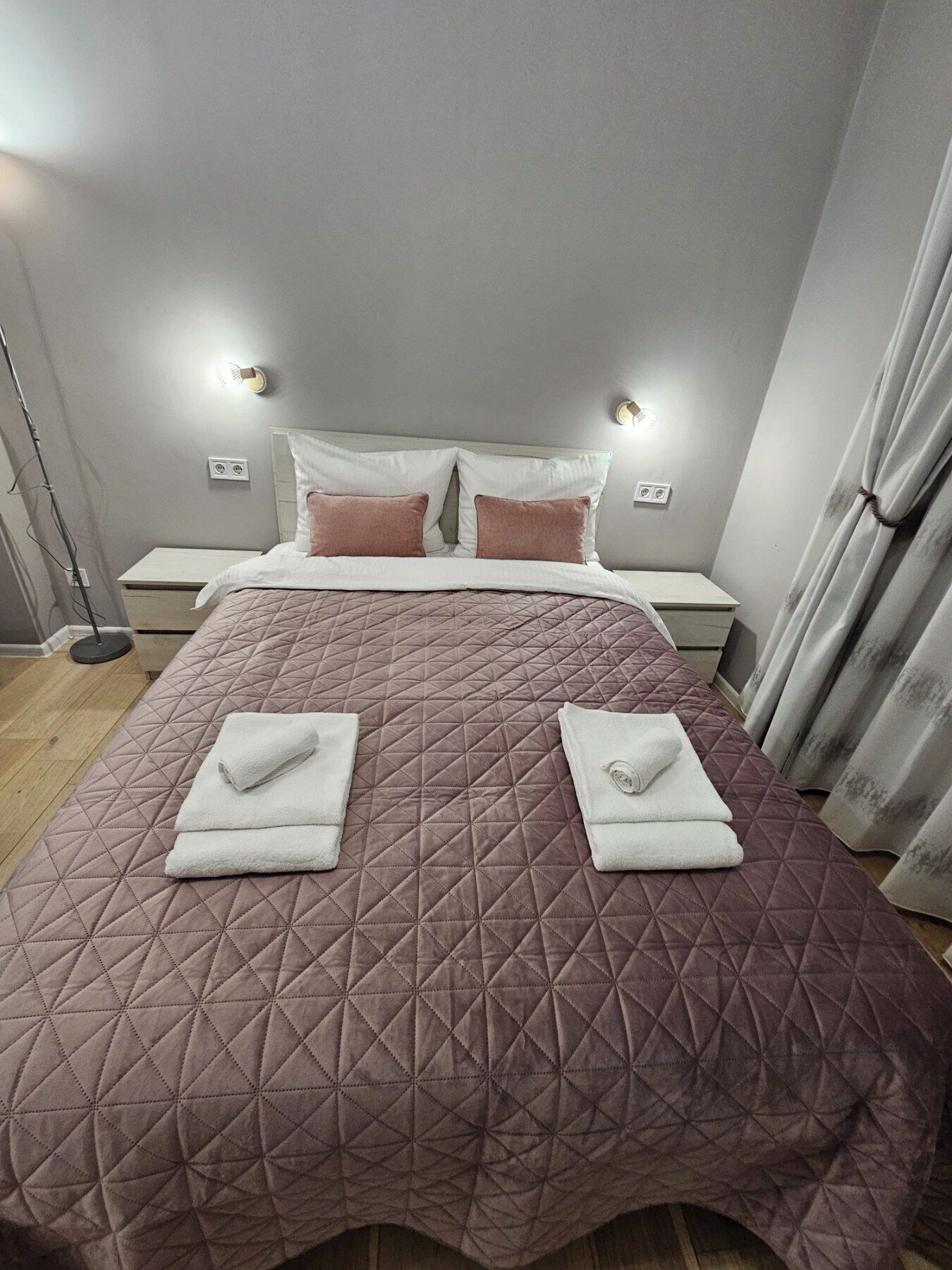 Una cama bien hecha con un cubreacolchado, dos almohadas y dos toallas dobladas sobre la cama.