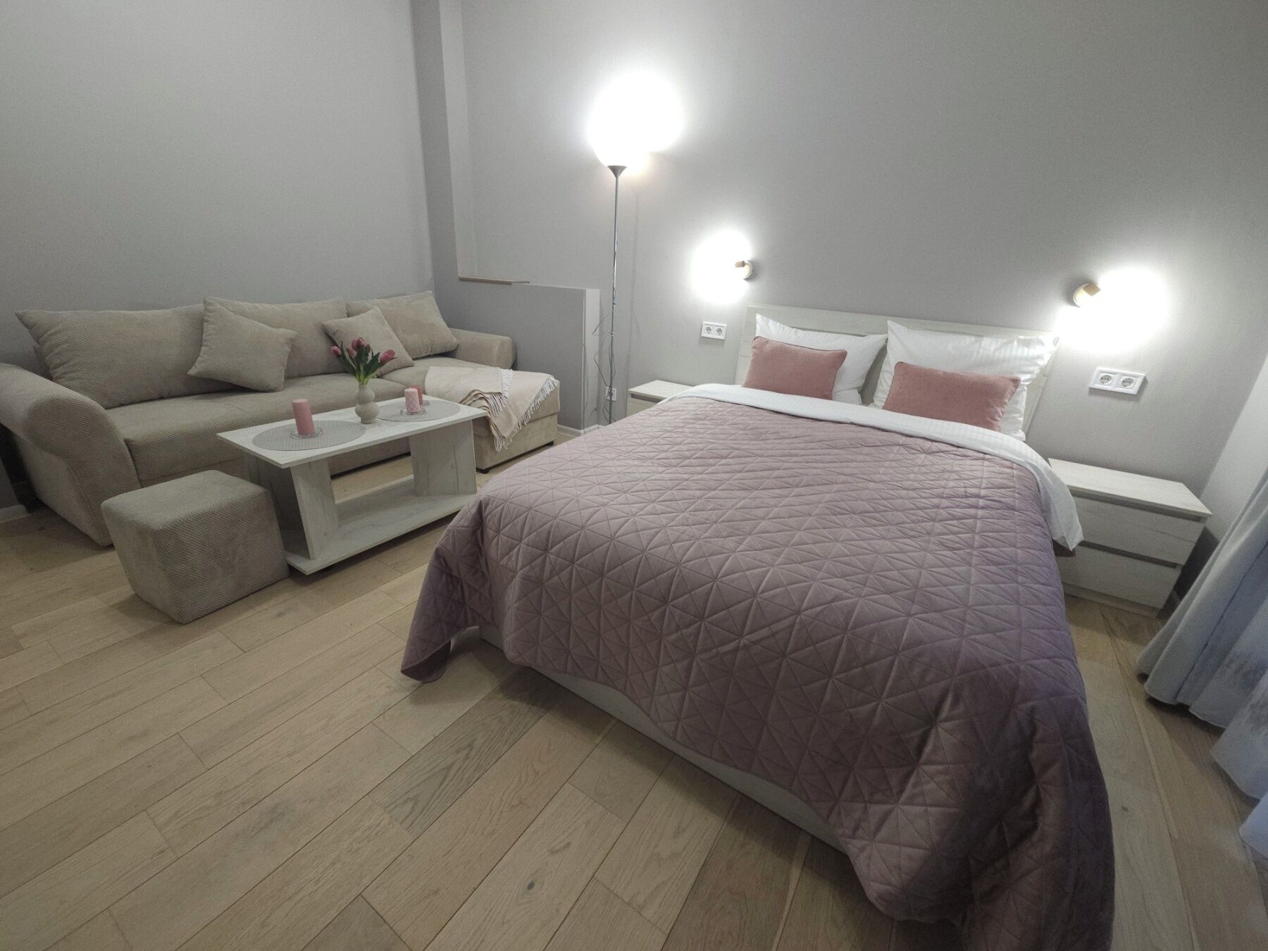 Un dormitorio con cama, sofá, mesa de centro y lámparas de noche.