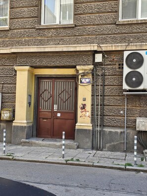 A building facade with a double door, a small window, and an air conditioning unit.