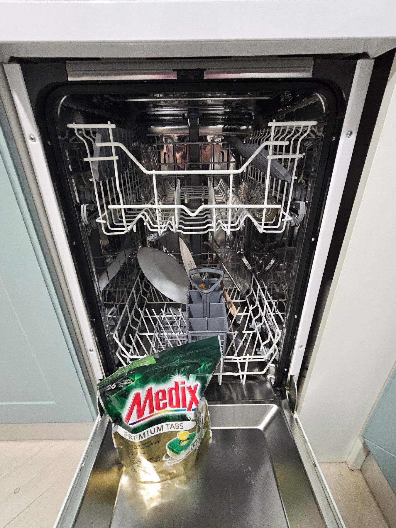 Un lave-vaisselle ouvert, avec un sachet de pastilles Medix Premium à l’intérieur.