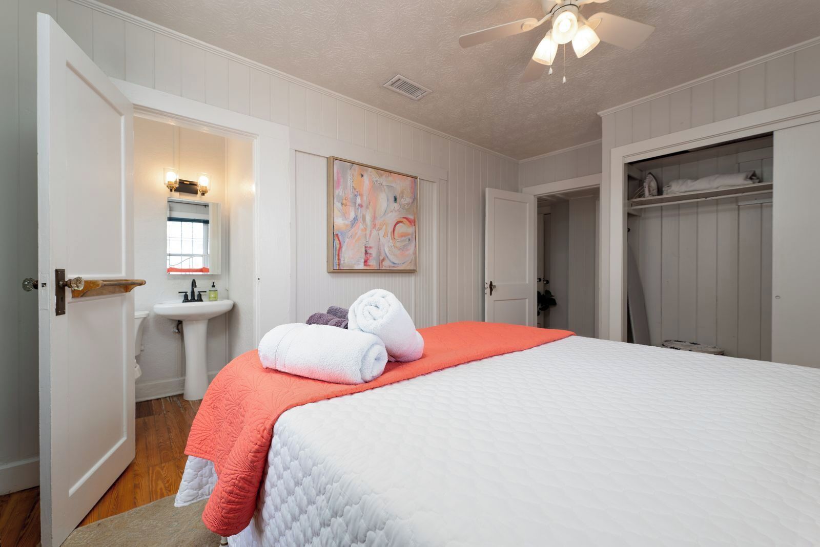 Une chambre à coucher avec un lit, une table de chevet, un miroir, un tableau et une armoire.